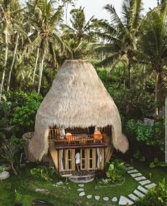 a small hut with a straw roof on top of it at DD Bamboo Lodge in Gianyar