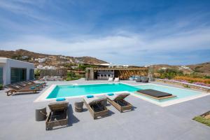 een zwembad op een patio met stoelen en een huis bij Villa Leda Mykonos in Mykonos-stad