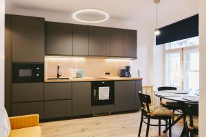 a kitchen with black cabinets and a table with chairs at Kullassepa Boutique Apartments - Square View in Tallinn