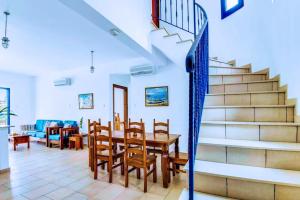 a dining room with a table and chairs and stairs at Azzurro Holiday Villas in Peyia
