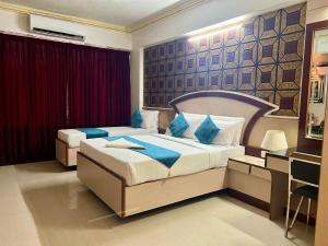 a hotel room with two beds with blue pillows at The Grand Krishna Rooms in Bengaluru