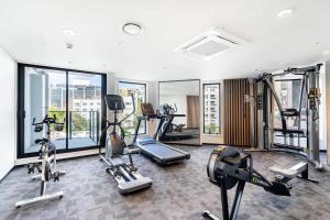 a gym with several treadmills and machines in a room at Stunning Studio Close to SkyTower - Pool Gym Sauna in Auckland