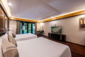 ein Hotelzimmer mit zwei Betten und einem Fernseher in der Unterkunft Hon Tam Resort in Nha Trang