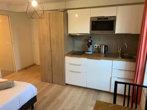 a small kitchen with white cabinets and a microwave at Cosy Corbeil Studio RerD 700m N7 in Corbeil-Essonnes