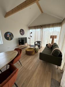 ein Wohnzimmer mit Sofa und Tisch in der Unterkunft Luxe 10-persoons vakantiehuis Lauwersmeer, Friesland in Anjum