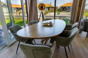 ein Esszimmer mit einem Holztisch und Stühlen in der Unterkunft Luxe 10-persoons vakantiehuis Lauwersmeer, Friesland in Anjum