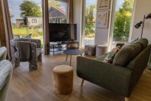 ein Wohnzimmer mit Sofa und Fernseher in der Unterkunft Luxe 10-persoons vakantiehuis Lauwersmeer, Friesland in Anjum