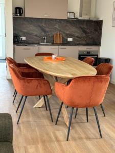 eine Küche mit einem Holztisch und orangefarbenen Stühlen in der Unterkunft Luxe 10-persoons vakantiehuis Lauwersmeer, Friesland in Anjum