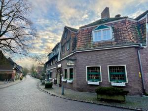 a large brick building on a cobblestone street at Hotel-Restaurant Schraeder in Greven