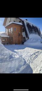 a house covered in snow in front of it at Alpha Ski Apartmani in Jahorina