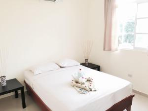 a bedroom with a bed with white sheets and a window at Costambar Beach Seaside Apartment in San Felipe de Puerto Plata