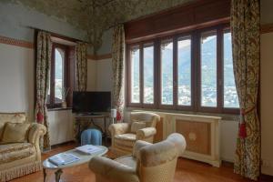 a living room with chairs and a tv and windows at La Villa Regia in Torno