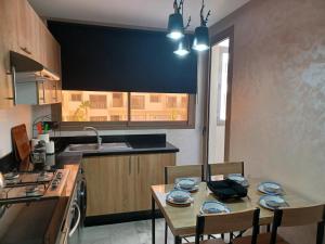 a kitchen with a table and chairs and a kitchen with a sink at Lovely & Comfy Long and Short Stay at Nouacer-Casa 2-Bedroom Apartment in Nouaceur
