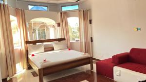 a small room with a bed and a red couch at skyport villa in Zanzibar City +18 photos