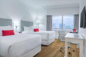 a hotel room with two beds and a desk at NH Collection Plaza Santiago in Santiago