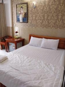 a bedroom with a white bed with a picture on the wall at Khách Sạn Thiên Phúc in Ho Chi Minh City +3 photos