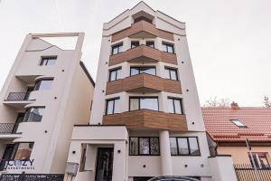 ein hohes weißes Gebäude mit Holzbalkonen in der Unterkunft COZY Luxury Collection - PREMIUM APARTHOTEL in Braşov