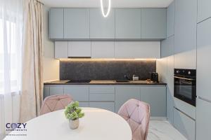 eine Küche mit weißen Schränken und einem Tisch mit Stühlen in der Unterkunft COZY Luxury Collection - PREMIUM APARTHOTEL in Braşov