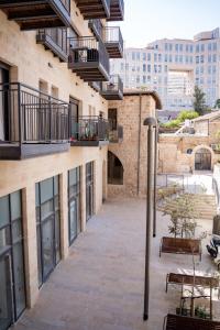 une cour vide d'un bâtiment avec bancs et balcons dans l'établissement Luxury 3 BDR In The Heart Of Jerusalem By Isrentals, à Jérusalem