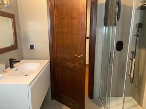 een badkamer met een houten deur naast een wastafel en een douche bij Casale Monte Oliviero - Bike Friendly B&B in Rome