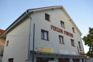 a white building with a sign on the side of it at Penzion POMPANO in Hlohovec