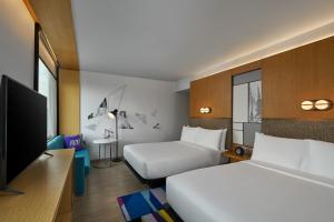 a hotel room with two beds and a flat screen tv at Aloft by Marriott Bangkok Sukhumvit 11 in Bangkok +131 photos
