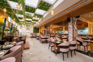 a restaurant with tables and chairs and plants at Ramee Tarang Hotel Indore in Indore