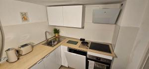 una piccola cucina con armadi bianchi e lavandino di Weilerswist Haus für große Gruppen Monteurshaus bis 8 Personen, Einzelbetten, 4 Schlafzimmer, 1 Küche, Terrasse Innenhof, Parkplatz a Weilerswist
