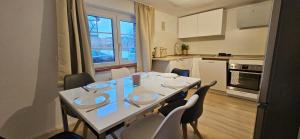 una cucina con tavolo e sedie bianchi, tavolo e sedie. di Weilerswist Haus für große Gruppen Monteurshaus bis 8 Personen, Einzelbetten, 4 Schlafzimmer, 1 Küche, Terrasse Innenhof, Parkplatz a Weilerswist