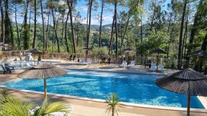 einen Pool mit Sonnenschirmen, Stühlen und Tischen in der Unterkunft Village de Chalets in Joyeuse
