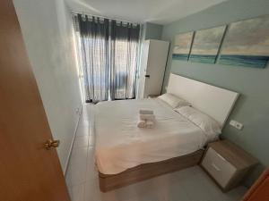 a small bedroom with a white bed with a scale on it at LV Aquario I in La Pineda +2 photos