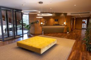 a living room with a yellow ottoman on a rug at Hotel Xalet del Golf in Puigcerdà