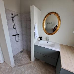 a bathroom with a sink and a shower with a mirror at Eltvedhus Feriebolig in Hjørring