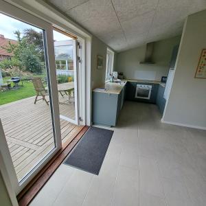 a kitchen with a door open to a patio at Eltvedhus Feriebolig in Hjørring +10 photos