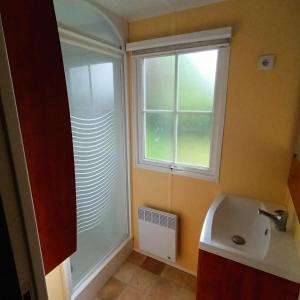 een badkamer met een wastafel en een raam bij Camping Baroudeurs in Lagraulière