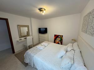 a bedroom with a white bed and a television at Casa Eva in Los Llanos de Aridane