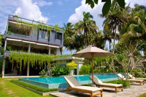 a resort with a swimming pool with chairs and an umbrella at Ivory Resort Dikwella in Dickwella