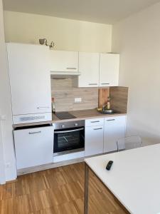 a white kitchen with white cabinets and a sink at Modernes Apartment in der Innenstadt Klagenfurt in Klagenfurt