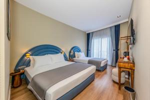 a hotel room with two beds and a desk at Nenessa Airport Hotel in Arnavutköy