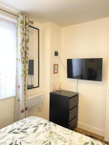 a bedroom with a bed and a flat screen tv at Norwich 1st Floor Apartment in Goodmayes