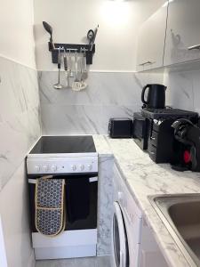 a white kitchen with a stove and a sink at Norwich 1st Floor Apartment in Goodmayes +4 photos