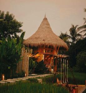 a small hut with a straw roof and a fence at DD Bamboo Lodge in Gianyar +13 photos