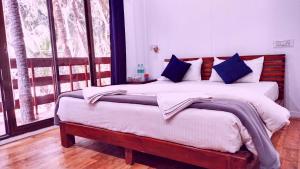 a bedroom with a large bed with blue pillows at Samant Beach Resort in Malvan +143 photos