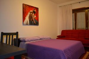 a bedroom with a purple bed and a red couch at B&B Visconti in Lido di Ostia