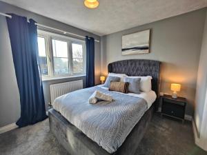 a bedroom with a large bed with blue curtains at Cedar - AwayOnBusiness in Eastleigh