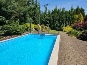 a man is standing next to a swimming pool at Ferienhaus Lipowa in Lipowa