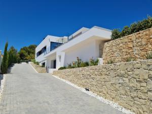 a stone wall next to a white house at Villa Benimaurell Relax Beach Moraira in Moraira