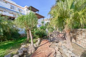 a garden with palm trees in front of a building at La Casita Azul in Almuñécar