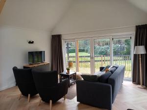 a living room with a couch and chairs and a television at De Eekhoorn in Ugchelen