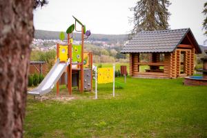 a playground with a slide and a log cabin at Main Spessart Terrasse Hotel in Gemünden